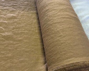 Könnte beinhalten: Eine Rolle braunen Stoffes mit strukturierter Oberfläche. Der Stoff ist teilweise abgerollt und zeigt einen ausgefransten Rand. Das Material scheint weich und fließend zu sein, geeignet für Bekleidungs- oder Heimdekorationsprojekte.