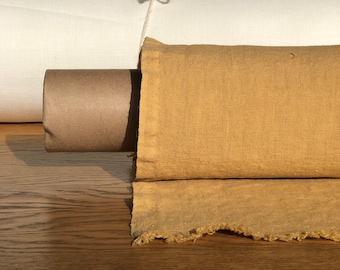 May include: A roll of light brown linen fabric with a rough, textured surface. The fabric is rolled up and tied with a piece of twine. The fabric is sitting on a wooden surface.
