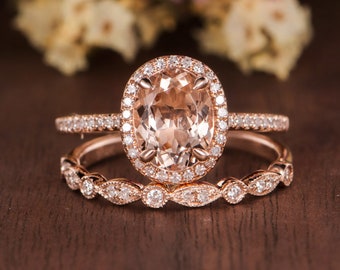 May include: A rose gold engagement ring set with a large oval morganite center stone and a halo of smaller diamonds. The band is also set with diamonds.