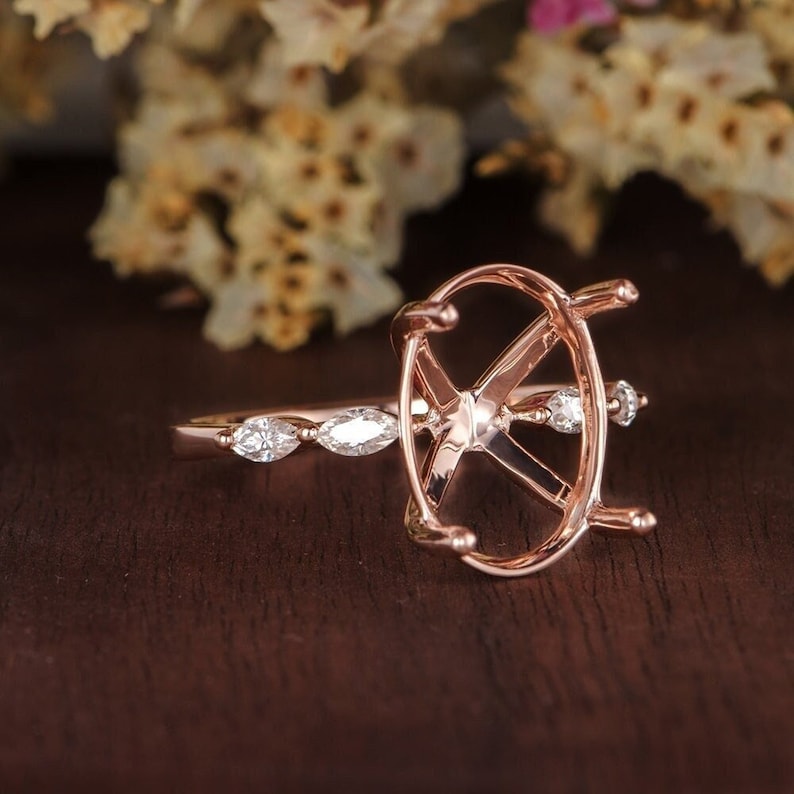 May include: A rose gold ring setting with an oval shaped center stone and a pave band of marquise shaped accent stones.