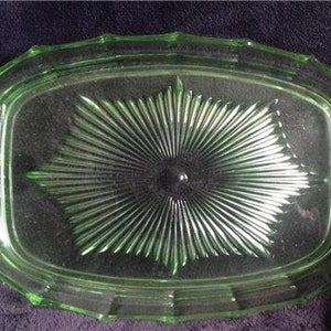 May include: A vintage green glass serving dish with a starburst pattern. The dish has a raised rim and a smooth, glossy finish.