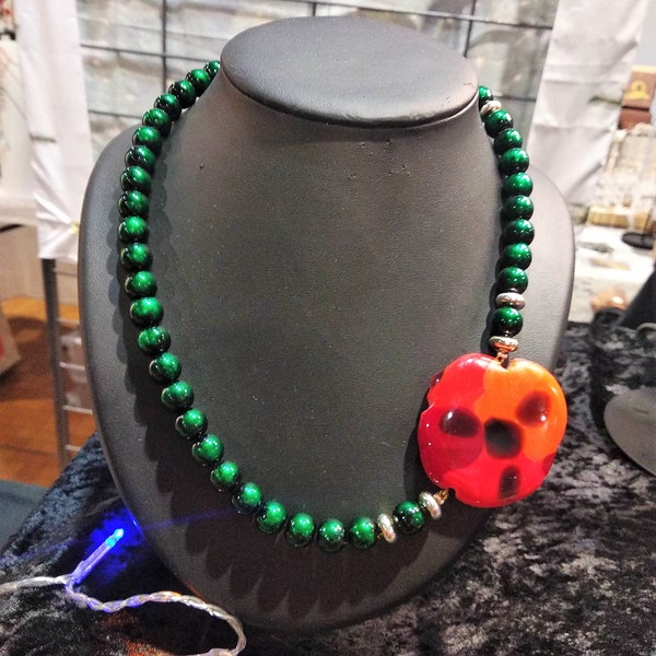 Collier fleur composé d'un bijou orange rouge noir en verre fusinget d'un rang de perles de vertes en verre brillantes