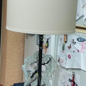 May include: A white lampshade with a black metal base and a glass sculpture. The sculpture is made of clear glass and has a variety of shapes and sizes.