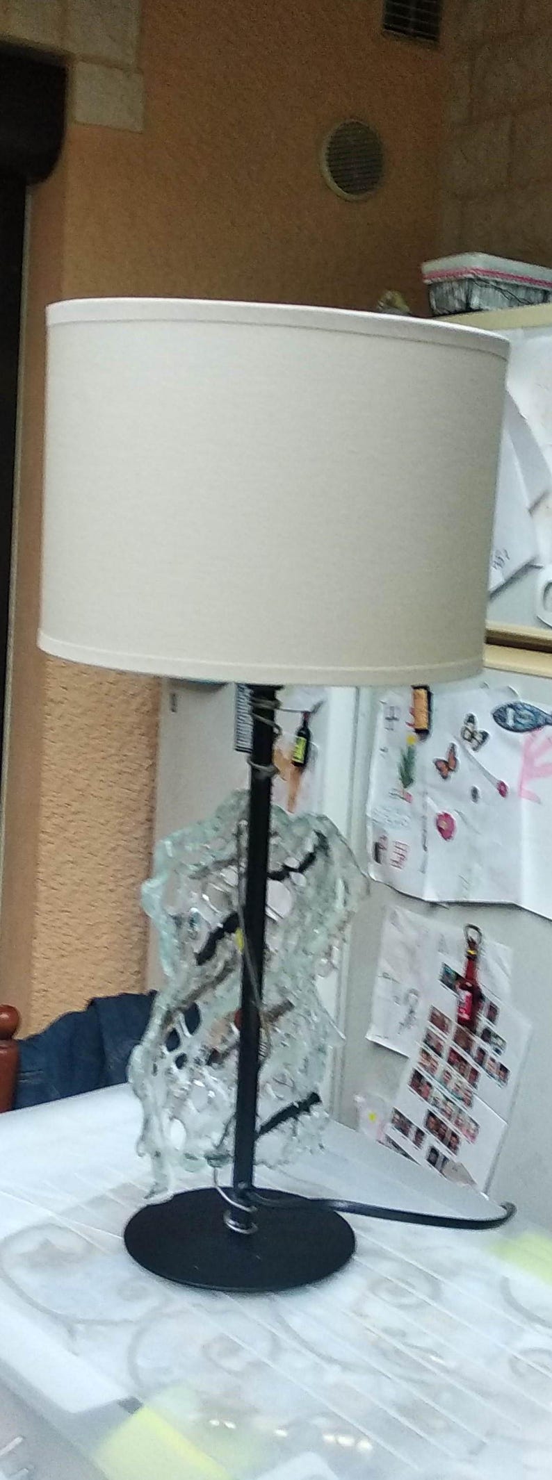 May include: A white lampshade with a black metal base and a glass sculpture. The sculpture is made of clear glass and has a variety of shapes and sizes.