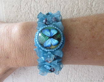 Bracelet manchette papillon lumineux, avec un cabochon en verre, des perles fleurs, et du ruban d'organza