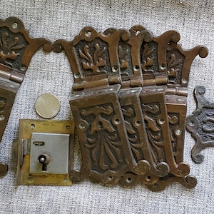 May include: A set of ten antique brass hinges with intricate floral designs. The hinges are in excellent condition and would be a beautiful addition to any home.