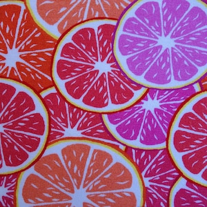 Könnte beinhalten: Ein weißer Stoff mit einem sich wiederholenden Muster aus rosa, roten und orangen Zitrusfrüchtescheiben. Die Fruchtscheiben sind in einem zufälligen Muster angeordnet.