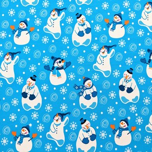 Könnte beinhalten: Ein blauer Stoff mit einem sich wiederholenden Muster aus weißen Schneemännern mit schwarzen Hüten, Schals und Fäustlingen. Die Schneemänner sind von weißen Schneeflocken und weißen Kreisen umgeben.