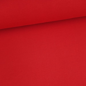 Könnte beinhalten: Eine Rolle leuchtend roten Stoffes. Der Stoff hat eine glatte, gleichmäßige Textur.