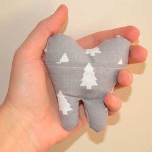 May include: A gray tooth-shaped pillow with a white Christmas tree pattern.