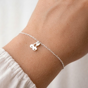 Peut inclure: Un bracelet à chaîne fine de couleur argentée doté d'un petit pendentif plat en forme de cerise. Le pendentif se compose de deux éléments circulaires reliés par une courte tige, suspendus à la fine chaîne en métal poli entourant le poignet.