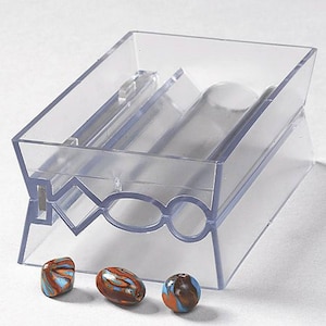 Puede incluir: Un rodillo de cuentas de plástico transparente con tres cuentas de vidrio de colores. El rodillo tiene una ranura para insertar una cuenta y un mango para hacer rodar la cuenta.