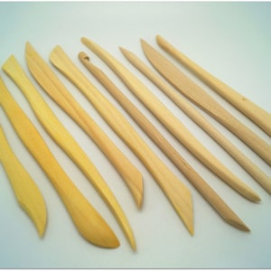 Peut inclure: Un ensemble de 12 outils de sculpture en bois de différentes formes et tailles. Les outils sont en bois naturel et ont une couleur brun clair.