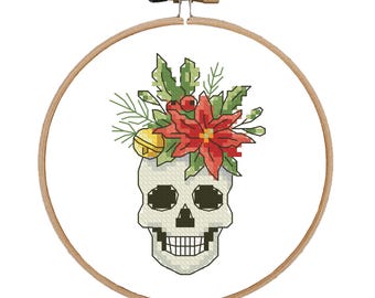 May include: A white skull with a red poinsettia and green foliage on top. The skull has black eyes and a toothy grin.