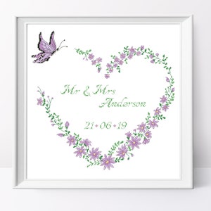 Peut inclure: Un cadre blanc avec un fond blanc et un papillon violet volant au-dessus d'une couronne de fleurs violettes en forme de cœur. Le texte "Mr. & Mrs. Anderson 21.06.19" est écrit en cursive verte.