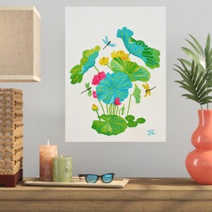 This lotus flower art print is a copy of my acrylic painting of a vibrant lotus pond arrangement on a textured white background. Large lotus leaves in shades of turquoise, teal, and bright green with distinct yellow-green veins dominate the center. The composition features yellow and bright pink lotus flowers in bloom, and small buds. Three dragonflies—one blue, one green, and one yellow—hover around the foliage. My artist's signature, "JeC," is written in blue in the bottom right corner.