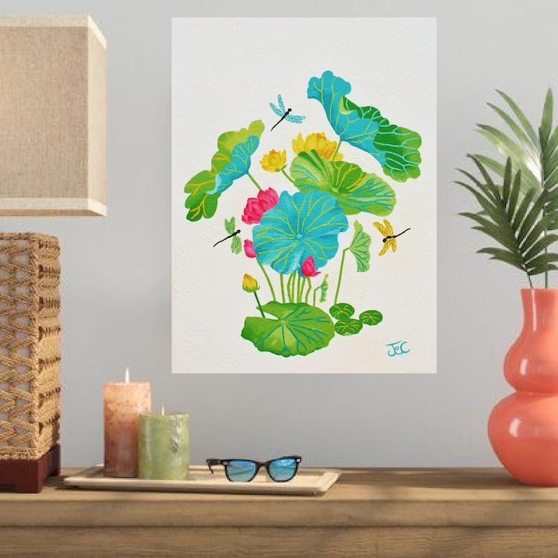 This lotus flower art print is a copy of my acrylic painting of a vibrant lotus pond arrangement on a textured white background. Large lotus leaves in shades of turquoise, teal, and bright green with distinct yellow-green veins dominate the center. The composition features yellow and bright pink lotus flowers in bloom, and small buds. Three dragonflies—one blue, one green, and one yellow—hover around the foliage. My artist's signature, "JeC," is written in blue in the bottom right corner.