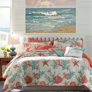 May include: A bed with a white headboard and a coastal-themed quilt. The quilt features a pattern of coral, seashells, and starfish in shades of coral, teal, and beige. A painting of a beach scene hangs above the bed.