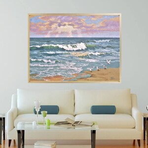 May include: A framed artwork depicting a coastal scene. The painting showcases ocean waves in shades of blue and green, crashing onto a sandy beach. Several seagulls are on the shore. The sky features a blend of pink, purple, and blue hues, suggesting a sunrise or sunset.