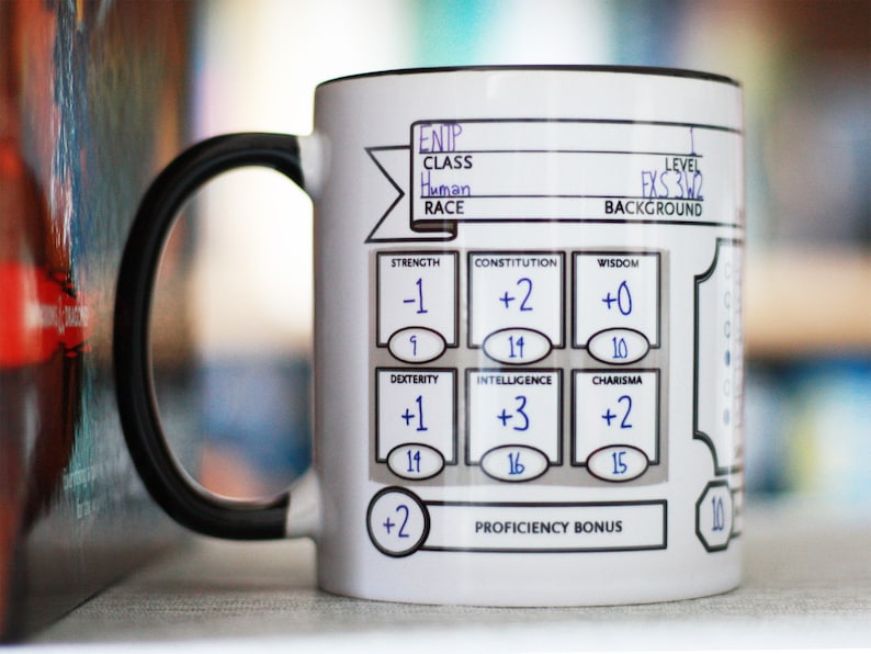 May include: White ceramic mug with a black handle. The mug has a printed Dungeons and Dragons character sheet with the following information: ENTP, Class: Human, Level: 3, Background: FXS. The character sheet also includes stats for Strength, Constitution, Wisdom, Dexterity, Intelligence, and Charisma.