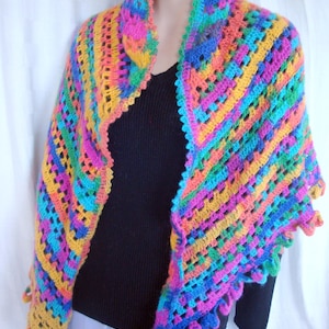 Peut inclure: Un châle en crochet coloré avec une bordure en franges. Le châle est réalisé avec une variété de couleurs vives, dont le rose, le bleu, le vert, le jaune et l'orange.