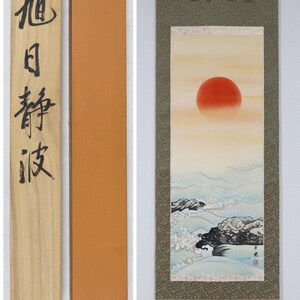 Può includere: Dipinto su rotolo giapponese raffigurante un sole rosso su un paesaggio marino con onde e rocce. La pergamena è incorniciata con tessuto fantasia e include una scatola di legno con calligrafia giapponese.