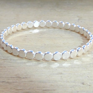 May include: A silver bangle bracelet made of small, round beads.