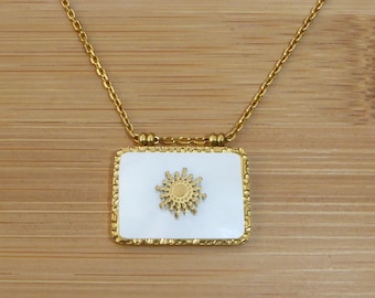 May include: A gold chain necklace with a white square pendant featuring a gold sun design.