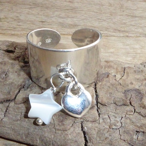 Può includere: Un anello regolabile in argento con un ciondolo a forma di stella bianca e cuore argentato.
