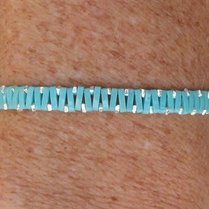 Peut inclure: Un bracelet turquoise et argent avec un motif tissé.