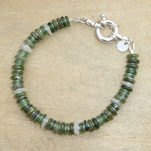 May include: A green and white gemstone bracelet with a silver clasp. The bracelet is made of small, round beads.