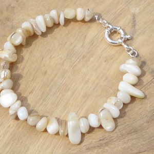 May include: A white shell bracelet with a silver clasp. The bracelet is made of natural, irregular shaped shells.