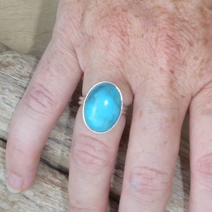 Peut inclure: Une bague en argent avec une grande pierre ovale en turquoise.
