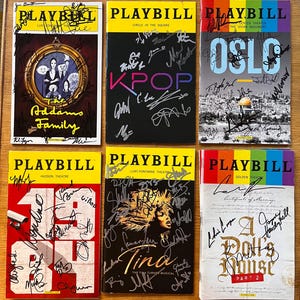 Puede incluir: Seis programas de teatro Playbill, cada uno con una pancarta superior amarilla y varios títulos de espectáculos. Los títulos incluyen "The Addams Family", "KPOP", "OSLO", "1984", "Tina" y "A Doll's House, Part 2". Cada Playbill está firmado.