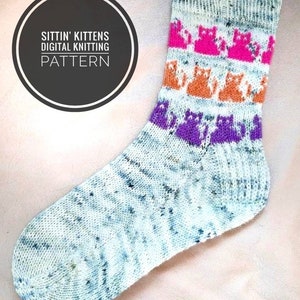 Puede incluir: Un calcetín tejido con una base blanca y un patrón moteado. El calcetín tiene tres bandas de gatitos coloridos, en rosa, naranja y morado.