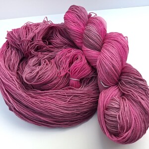 May include: A skein of pink and purple yarn with a gradient effect. The yarn is soft and fluffy, and it would be perfect for knitting or crocheting.