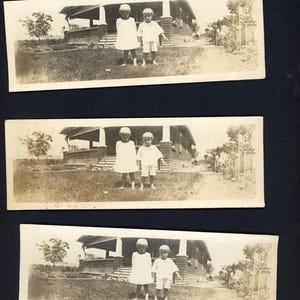 Op de afbeelding: Drie vintage zwart-witfoto's van twee jonge kinderen die poseren voor een huis. De kinderen dragen lichtgekleurde kleding en hoeden. Het huis heeft een veranda en is omgeven door gras en bomen.