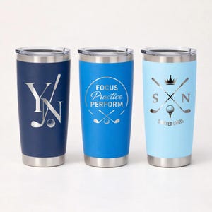 May include: Three insulated tumblers in navy, blue, and light blue. Each tumbler features a silver design related to golf. The navy tumbler has "YN" with a golf club and ball. The blue tumbler says "FOCUS Practice PERFORM". The light blue tumbler has "SXN" with a golf ball and club.