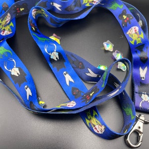 May include: A blue lanyard with a repeating pattern of black and green creatures. The lanyard has a silver metal clasp.