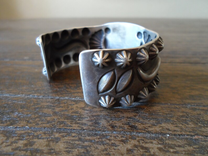 K&ouml;nnte beinhalten: Ein silbernes Armband mit aufwendigen Designs, darunter ein Halbmond, Sterne und Bl&auml;tter. Das Armband ist aus massivem Silber gefertigt und hat eine polierte Oberfl&auml;che.