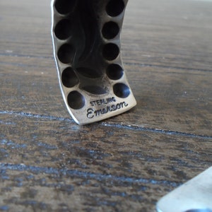 K&ouml;nnte beinhalten: Nahaufnahme eines silbernen Armbands mit einer strukturierten Oberfl&auml;che und einer gepr&auml;gten Inschrift mit der Aufschrift "STERLING E.MARSON".