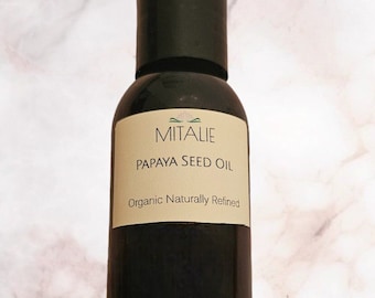 May include: A dark brown glass bottle with a black cap. The label reads "MITALIE PAPAYA SEED OIL Organic Naturally Refined".