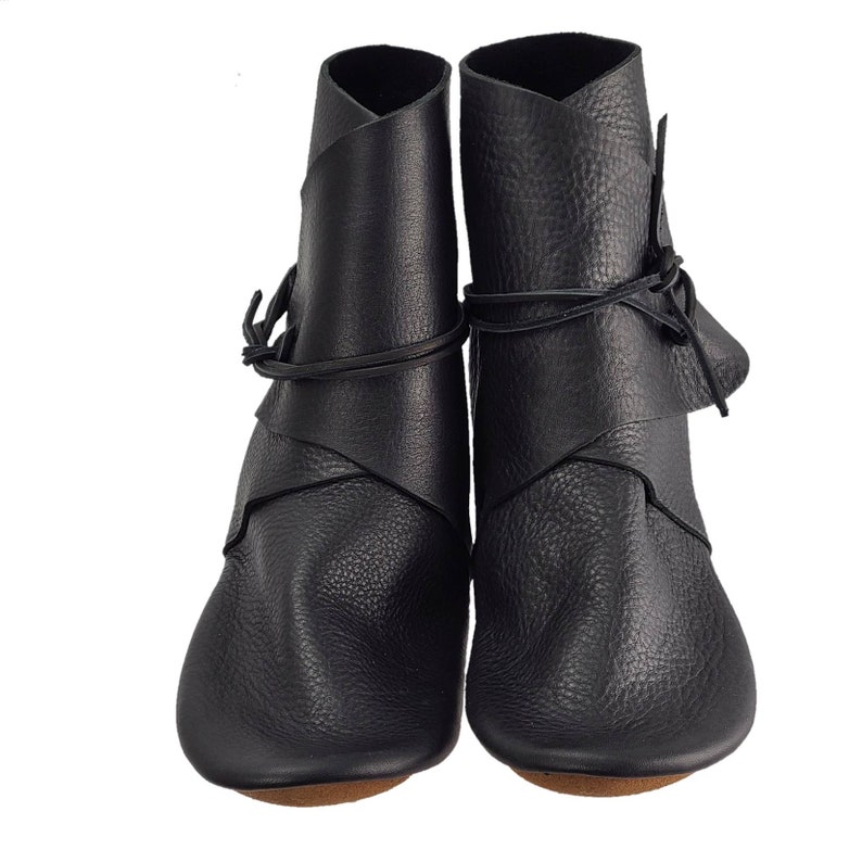 K&ouml;nnte beinhalten: Ein Paar schwarze Lederstiefel mit Schnallen. Die Stiefel haben eine spitze Zehenpartie und einen niedrigen Absatz.