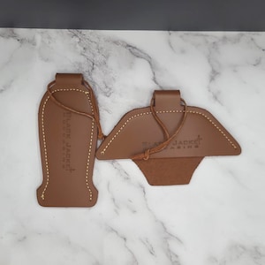 Puede incluir: Dos tiradores de botas de cuero marrón con un borde cosido y un lazo de cuerda. Los tiradores tienen el texto "Black Jacket" y "Made in USA" en relieve.