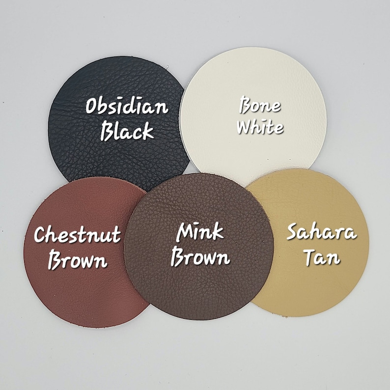 May include: Five round leather swatches in different colours and textures. The swatches are labelled "Obsidian Black", "Bone White", "Chestnut Brown", "Mink Brown", and "Sahara Tan".
