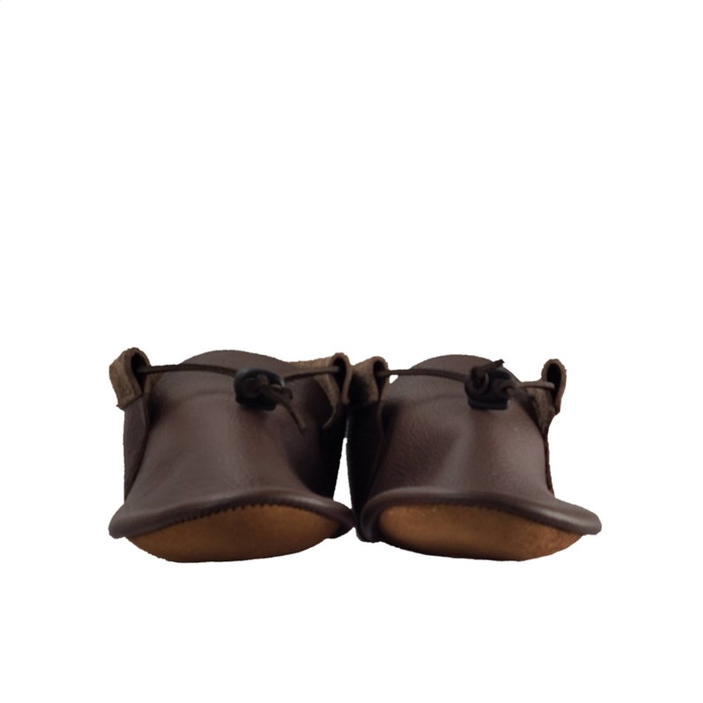 May include: A pair of brown leather moccasins with a simple design and a tie at the top.