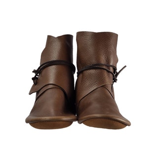 K&ouml;nnte beinhalten: Ein Paar braune Lederstiefel mit Schnallen. Die Stiefel haben eine abgerundete Spitze und einen niedrigen Absatz.