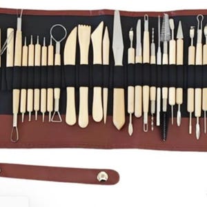 May include: A brown leather roll-up case containing 41 metal and wooden sculpting tools. The tools are arranged in rows and include a variety of shapes and sizes.