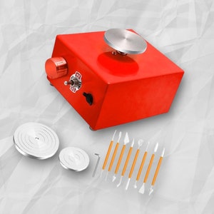 May include: Red pottery wheel with a white ceramic disc and a set of 10 orange and white sculpting tools. The pottery wheel has a knob to control the speed and a switch labelled "ON" and "OFF".