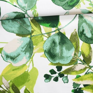 Groene bladerenstof op een witte achtergrond van katoen met oeko-text-print